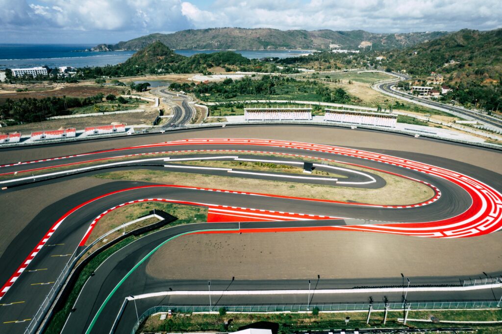 A stunning aerial shot of the Mandalika Circuit in Lombok, Indonesia, showcasing ocean and mountainous backdrop.